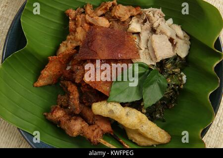 Nasi Campur babi guling. Balinesen Reis Reisgericht mit gedämpftem Reis garniert mit verschiedenen Gerichte der traditionellen Schweinebraten. Stockfoto