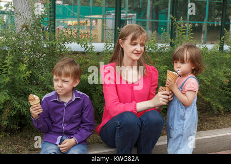 Mutter mit Jungen und Mädchen im Sommer Park essen Eis sitzen Stockfoto