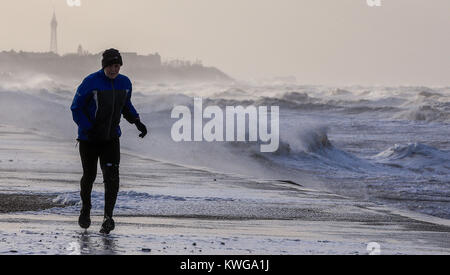 Ein Mann läuft hinter der rauen See in Blackpool als Sturm Eleanor Großbritannien mit heftigen Sturm Winde von bis zu 100 mph, verlassen Tausende von Häusern und Wohnungen, ohne Strom und schlagenden Verbindungen festgezurrt. Stockfoto