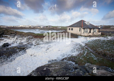 Anglesey, Wales, 3. Januar 2018. UK Wetter. Eine schwere Met Office Warnung hat für das fünfte Sturm der britischen Saison ausgestellt wurde Tropensturm Eleanor. Mit einem Anstieg der Gefahr durch die aktuelle Mond- und Gezeiten Hochwasserwarnungen für viele Bereiche zusammen mit gales Winde wahrscheinlich Schaden zu verursachen. Wellen und Wind Crash in Trearddur Bay auf Anglesey im Norden von Wales als Sea Foam ist über ein Haus zu verschlingen in der Nähe des Meeres © AlamyLive Nachrichten Stockfoto