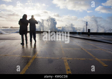 Anglesey, Wales, 3. Januar 2018. UK Wetter. Eine schwere Met Office Warnung hat für das fünfte Sturm der britischen Saison ausgestellt wurde Tropensturm Eleanor. Mit einem Anstieg der Gefahr durch die aktuelle Mond- und Gezeiten Hochwasserwarnungen für viele Bereiche zusammen mit gales Winde wahrscheinlich Schaden zu verursachen. Wellen und Wind Crash in Trearddur Bay auf Anglesey im Norden von Wales als Sturm Watchers beobachten die Wellen © DGDImages/Alamy leben Nachrichten Stockfoto