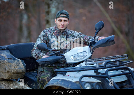 Junge Jäger auf ein Quad auf der Suche nach Spiel im Wald Stockfoto