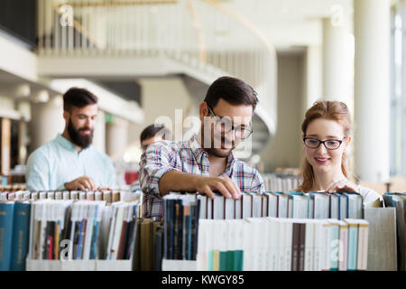 Glückliche junge Studenten studieren mit Büchern in der Bibliothek Stockfoto