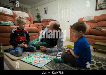 Ein grossvater Spielen Monopoly, Familie Brettspiel, über die Festtage mit seiner beiden Enkel im Vereinigten Königreich Stockfoto
