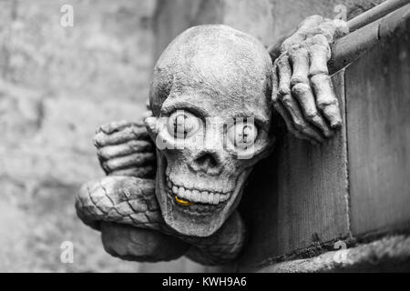 Zeitgenössische Skulptur einer Schlange mit menschlichen Händen und Schädel mit einer Goldmünze zwischen seinen Zähnen und £ Zeichen, die in der Kathedrale von Lincoln Stockfoto