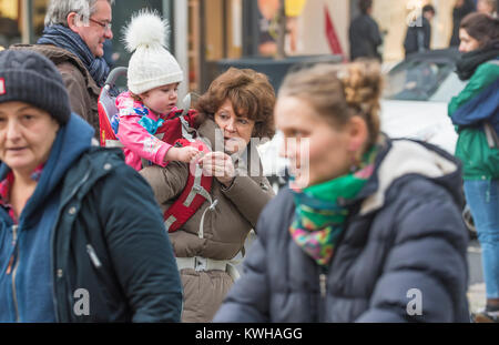 Frau, die ein Kind auf ihren Schultern, eine piggy zurück fahren, unter den Massen in einer belebten Straße in England, Großbritannien. Stockfoto