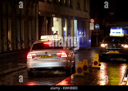 Taxis geparkt außerhalb Pub auf der Straße auf einem nassen und windigen Nacht in Belfast Nordirland UK Stockfoto