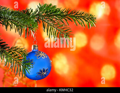 Blue Christmas Ball mit Weihnachten Zweig auf dem roten Hintergrund. Stockfoto