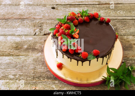 Schöne festliche Kuchen mit geschmolzener Schokolade mit Erdbeeren und Minze abgedeckt Stockfoto