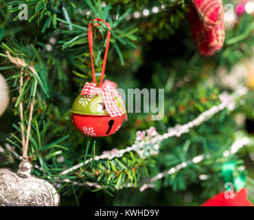 Rot und Grün Jingle bell Christbaumkugel mit star Grafik hängen am Weihnachtsbaum von einem kariertem Stoff Schleife Stockfoto
