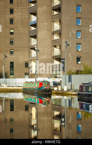 Marina an der Neuen Islington, Ancoats, Manchester, mored narrowboats als Häuser und neue Wohnung Gebäude spiegeln sich in der Stille Wasser Stockfoto