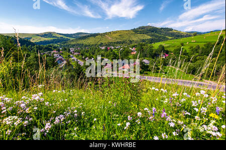 Schöne ländliche Landschaft im Sommer. Dorf entlang der Straße und die Felder mit Heuballen auf Hügeln. Blick von der grasigen Hang mit wilden Kräutern. Schön w Stockfoto