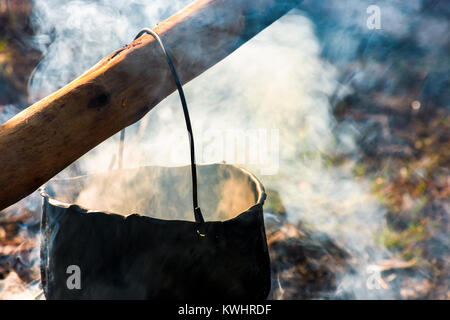 Kessel in den Dampf und Rauch auf offenem Feuer. Kochen im Freien Konzept. altmodische Weise essen zu machen Stockfoto