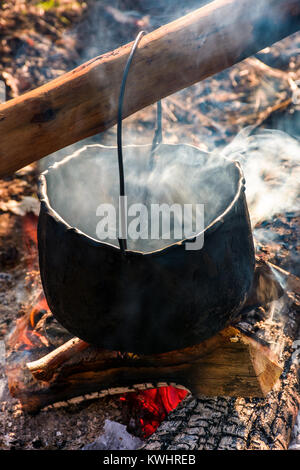 Kessel in den Dampf und Rauch auf offenem Feuer. Kochen im Freien Konzept. altmodische Weise essen zu machen Stockfoto