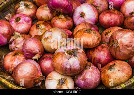 Viel rote Zwiebeln in das Fach auf der hölzernen Tisch Hintergrund auf dem Markt, Große Rote Zwiebeln Hintergrund Stockfoto