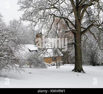 Reetdachhaus und Winter Bäume im Schnee im Dezember bei Batsford Arboretum, Cotswolds, Moreton-in-Marsh, Gloucestershire, England Stockfoto