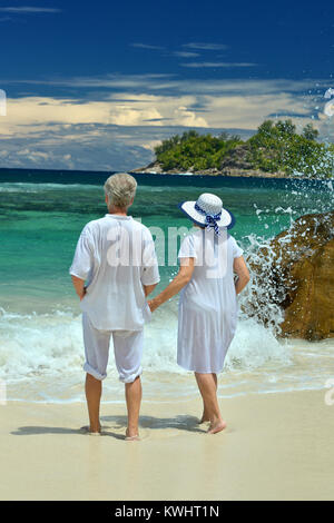 Ältere Paare stehen auf dem Strand mit Blick auf das Meer Stockfoto