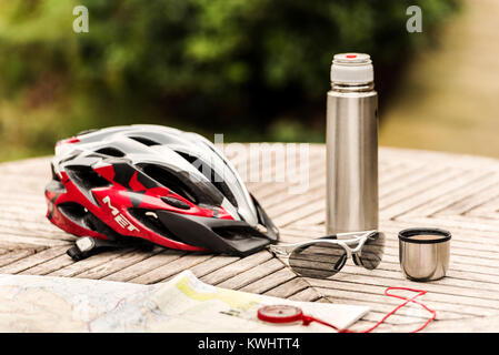 Radhelm und Brille auf Tabelle mit Kolben von Kaffee und Karte. Stockfoto