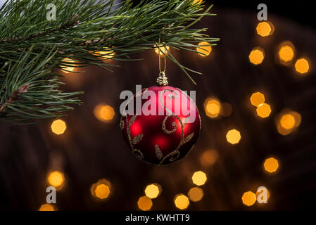 Rote Christbaumkugel hängen vom Weihnachtsbaum mit festlichen Lichter aus Fucus im Hintergrund. Stockfoto