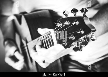 Die Schwarz-Weiß-Fotografie der Musiker spielen auf akustischer Gitarre. Nahaufnahme mit geringer Tiefenschärfe. Gitarre Leistung. Stockfoto