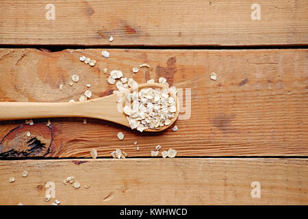 Löffel aus Holz mit Haferflocken über Holz- Muster Hintergrund. Stockfoto