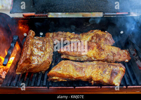 Schweinerippchen auf einem Grill über einem Holzfeuer grillen Baby zurück Rippchen über flammende Grill Stockfoto