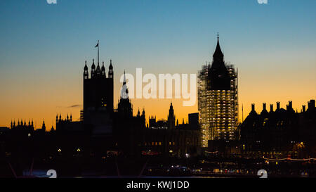 Die Houses of Parliament und Big Ben eingewickelt in Gerüstbau, gegen eine orange Himmel bei Sonnenuntergang. Stockfoto