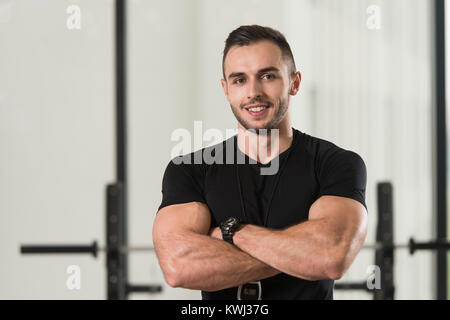 Gut aussehend Personal Trainer mit Stoppuhr In ein Fitness-Center Fitness-Studio stehen starke Stockfoto