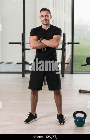 Gut aussehend Personal Trainer mit Stoppuhr In ein Fitness-Center Fitness-Studio stehen starke Stockfoto