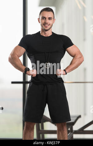 Gut aussehend Personal Trainer mit Stoppuhr In ein Fitness-Center Fitness-Studio stehen starke Stockfoto