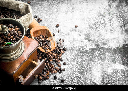 Handschleifmaschine mit Kaffeebohnen. Auf einem urigen Hintergrund. Stockfoto