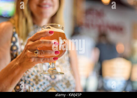 Lächelnde Frau mit einem Glas Bier in der gasthausbrauerei im Sommer Stockfoto