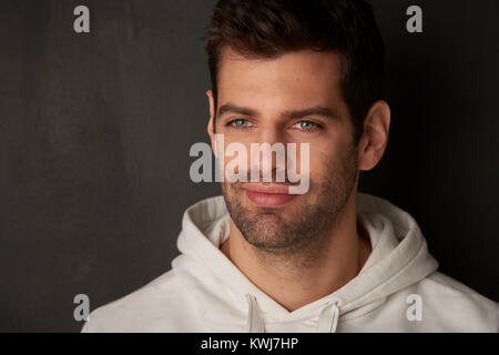 Nahaufnahme von einem gutaussehenden jungen Mann nachdenklich, während auf dunklem Hintergrund stehen. Stockfoto