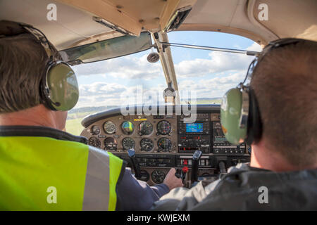 Pilot und Co Pilot in einem Piper PA-28 Cherokee Leichtflugzeug aus Northumbria Flugschule, Flughafen Newcastle, Tyne fliegen und Verschleiß, Großbritannien Stockfoto