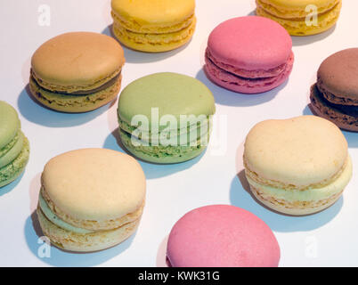 10 macarons in verschiedenen Farben aufgereiht auf einem weißen Hintergrund Stockfoto