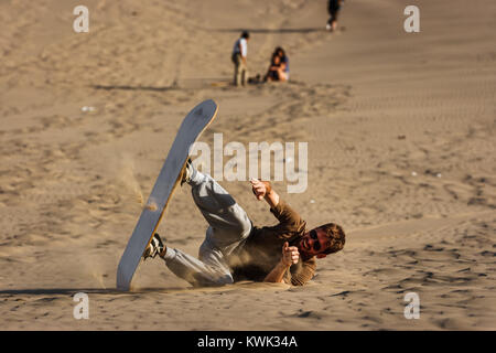 Bild eines jungen Mannes fallen, während bei Sonnenuntergang, Sandboarding, Ica Huacachina, Peru Stockfoto