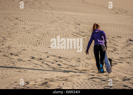 Bild einer jungen Frau bei Sonnenuntergang, Sandboarding, Ica Huacachina, Peru Stockfoto