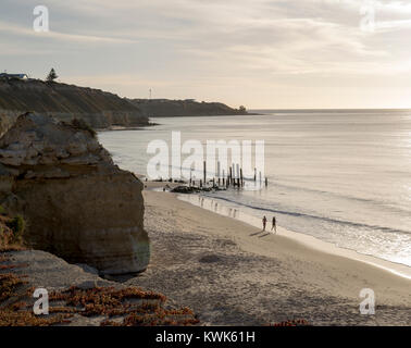 Port Willunga, South Australia - Dezember 16, 2017: Zwei weibliche Jogger am Strand entlang läuft mit der Ikonischen jetty Ruinen im Hintergrund. Ein p Stockfoto