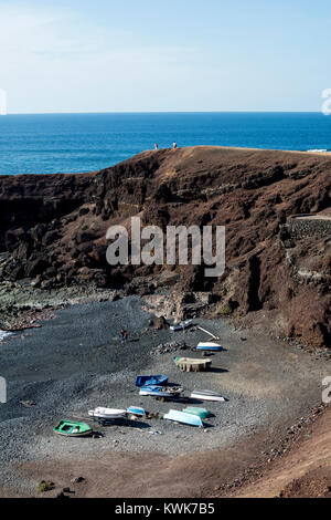 Boote auf einem kleinen schwarzen Strand von El Golfo, Lanzarote, Kanarische Inseln, Spanien. Stockfoto