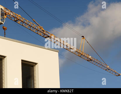Kranausleger vor einem strahlend blauen Himmel über der Ecke eines neuen Gebäudes, abstrakten Stockfoto