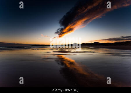 Cruden Bay, Aberdeenshire, Schottland. Farben eines Sonnenuntergangs sind in den Gewässern eines Ebbe am ersten Tag von 2018 wider Stockfoto