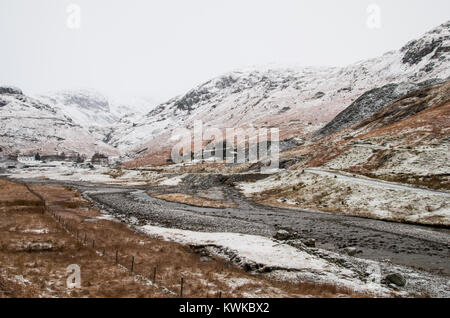 Ein Blick auf ein Tal mit wenigen Häusern, stream, schneebedeckte Berge und einigen früheren Steinbruch Aktivität. Stockfoto