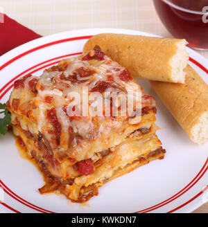 Portion Lasagne und Brot klebt auf einer Platte Stockfoto