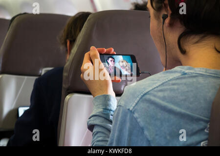 Männliche Beifahrer spielen eine Show, Film, Film oder Fernsehen auf seinem Handy - im Flugzeugmodus befindet, wird auf Maschinen des Typs Embraer air plane / Flugzeug / Flugzeug Stockfoto