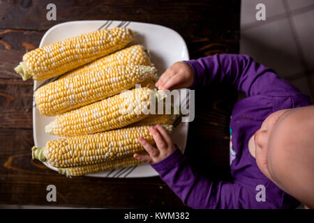 Ansicht von oben von Baby Mädchen berühren Hühneraugen in der Platte auf Stuhl Stockfoto
