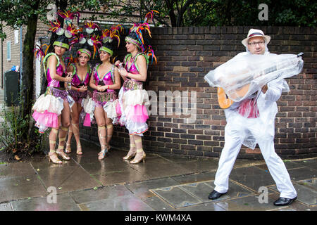 Tänzer aus dem Paraiso Schule von Samba, Schutz vor dem Regen vor der Notting Hill Carnival Parade, London, England, Vereinigtes Königreich Stockfoto