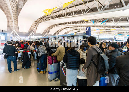 Japan, Kansia Flughafen, Innenraum. Internationaler Abflug Check-in Zone. Warteschlangen von Menschen, die in den Linien, vor allem in Asien, noch in am Check-in-Schalter während der langen Zeit nach drei Tag neues Jahr Urlaub. Stockfoto