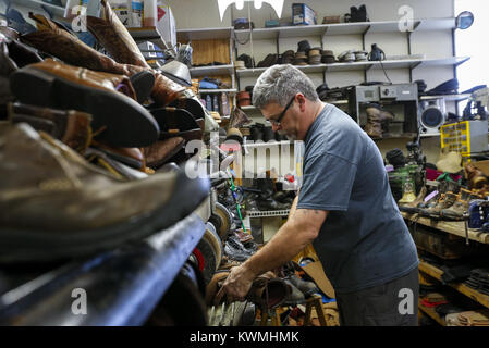 Moline, Iowa, USA. 28 Dez, 2016. Eigentümer Glen Delveau Sands ein Paar Stiefel, während durch einen Rückstand bei der Arbeit an den Schuh Krankenhaus in Moline am Mittwoch umgeben, 28. Dezember 2016. Delveau sagt, daß er jetzt Schuhe in Chargen arbeitet durch Schritte wie Schleifen, Stitching und polieren, um effizienter zu werden. Credit: Andy Abeyta/Viererkabel - Zeiten/ZUMA Draht/Alamy leben Nachrichten Stockfoto