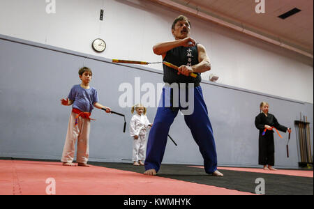 Moline, Iowa, USA. 28 Dez, 2016. Kung-Fu Lehrer John Morrow führt Robert Majchrzak, 8, von LeClaire, Zoe, 5, Mitte, und Schwester Zade Allmon, 8, von LeClaire durch ein Training mit nunchucks in seinem Studio in Moline am Mittwoch, 28. Dezember 2016. Morgen ist im Guinness Buch der Rekorde für den Abschluss 123 Liegestütze in einer Minute und sieht zu tun 1.000 pushups, 1000 Bein, und 1.000 Sit-ups in einer Stunde am kommenden Freitag auf seinem 65. Geburtstag. Credit: Andy Abeyta/Viererkabel - Zeiten/ZUMA Draht/Alamy leben Nachrichten Stockfoto