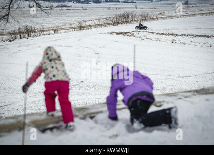 Davenport, Iowa, USA. 13 Mär, 2017. Allison Toft, 7, Fahrten mit einem schneemobil als Schwestern Morgan, 3, Links, und Katelynn, 10, sehen Sie beim Spielen im Schnee in Dixon am Montag, 13. März 2017. Ein paar Scott County Sno-Seekers Mitglieder zusammen, um für das, was die letzte Fahrt von einer spärlichen Schnee Saison werden könnte. Davenport erhalten nur über fünf Zentimeter Schnee über Nacht und den ganzen Tag Montag, einen kleinen Betrag für die Sno-Seekers, aber genug für das Letzte Hurra. Credit: Andy Abeyta/Viererkabel - Zeiten/ZUMA Draht/Alamy leben Nachrichten Stockfoto